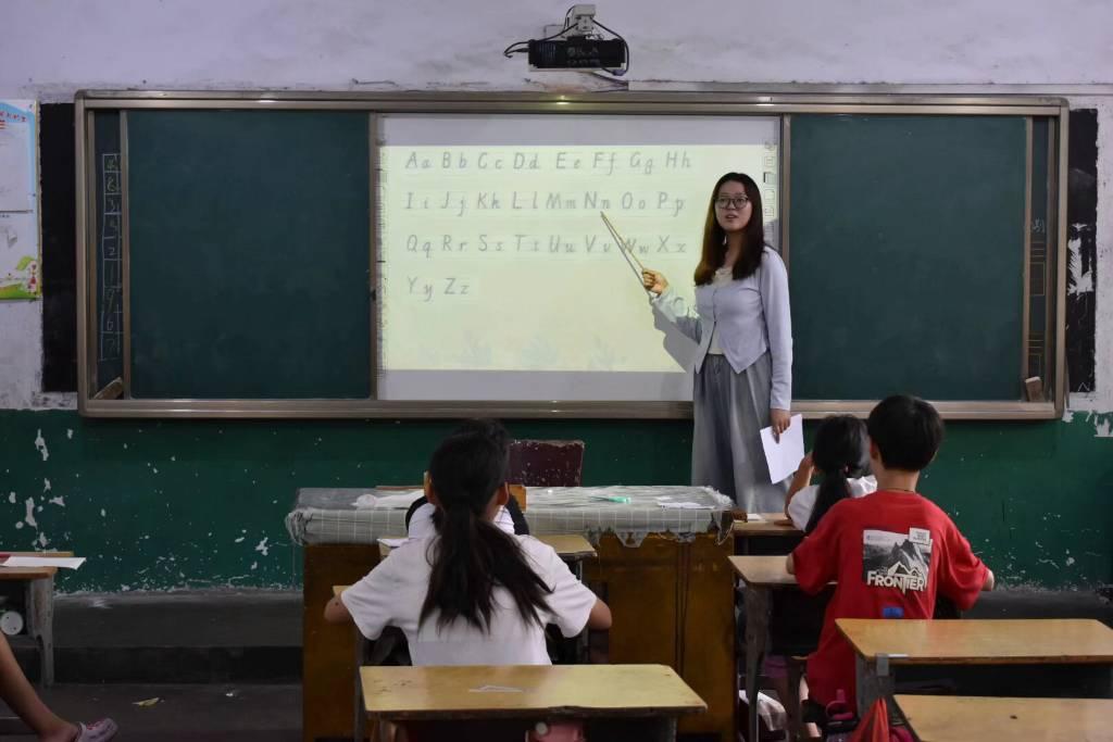 图为某节英语课，志愿者认真教授孩子们英语字母的正确书写方式及读音。