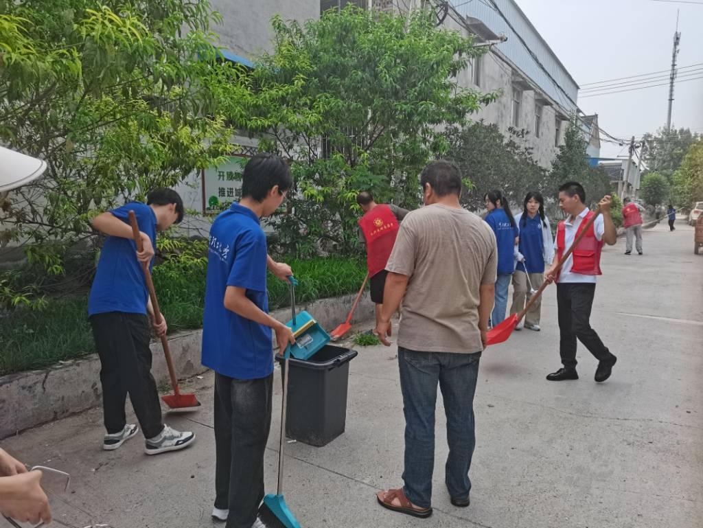 图为实践团成员在村干部指挥之下有序将垃圾倒入垃圾桶中，继续进行下一步工作