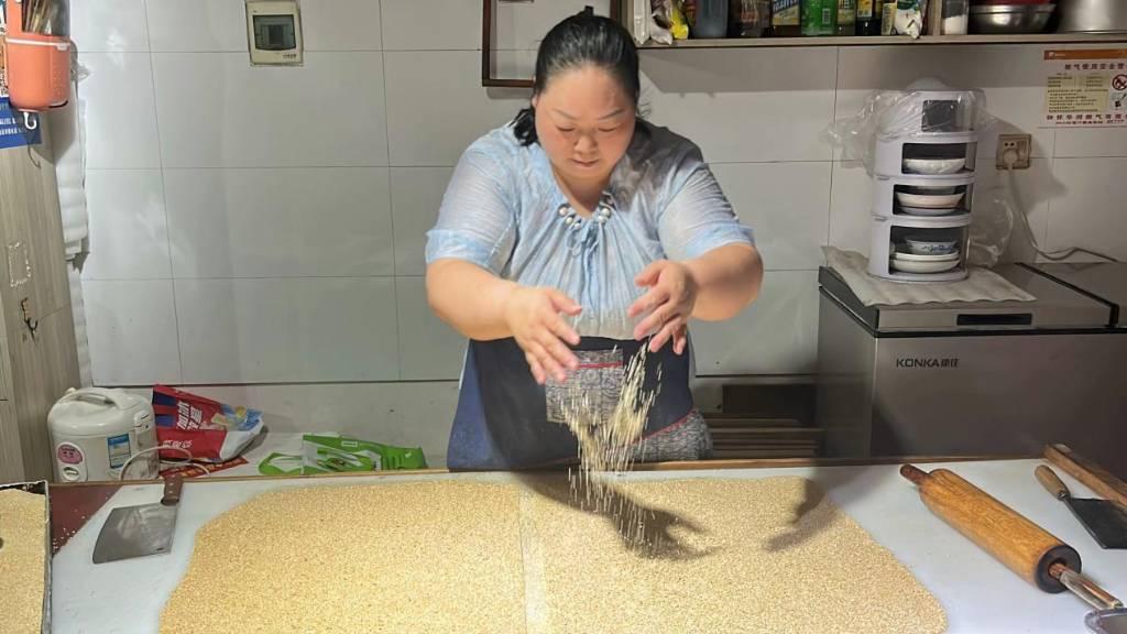 浓厚的麦芽糖浆裹上各类酥香的坚果碎，历经各道工序，最终制成长滩焦切。图为工作人员正在制作焦切。