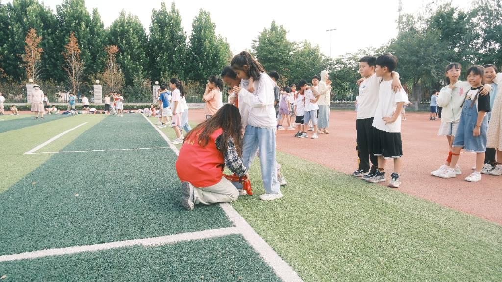 图为志愿者为参加两人三足比赛的学生进行赛前准备工作。 高建康 供图