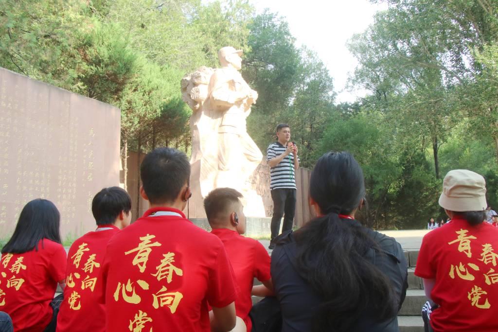 图为延安枣园革命旧址曹峰老师在张思德纪念广场，为实践团讲述张思德同志的英勇事迹。