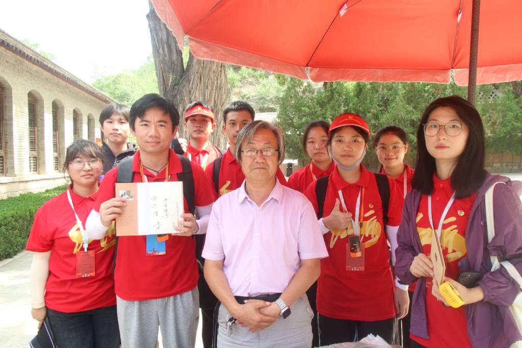 图为王家坪革命旧址著名作家花海洋先生为实践团赠书，并讲述走进延安的故事。