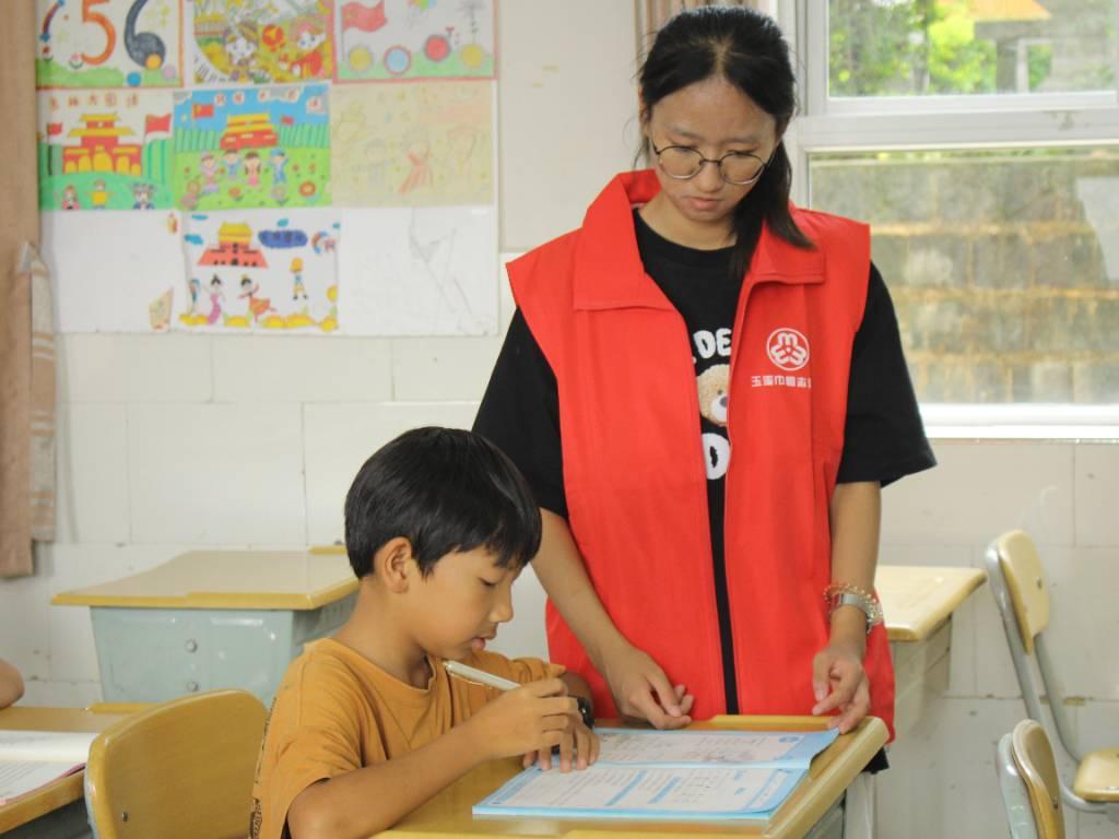 图为志愿者在辅导同学写作业。通讯员张艳琼摄