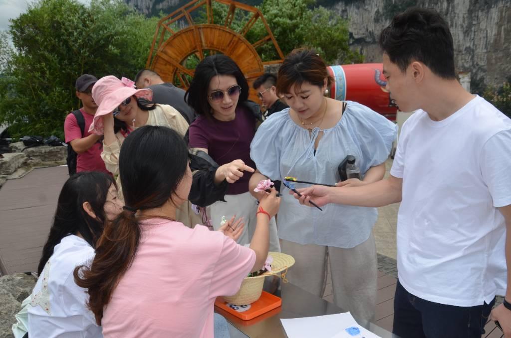 图为志愿者们向外地游客介绍通草画发簪