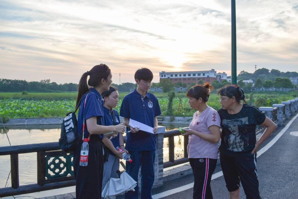 图为志愿者与村民交流乡村振兴带给社区的变化。大学生网报通讯员 刘赞华 摄