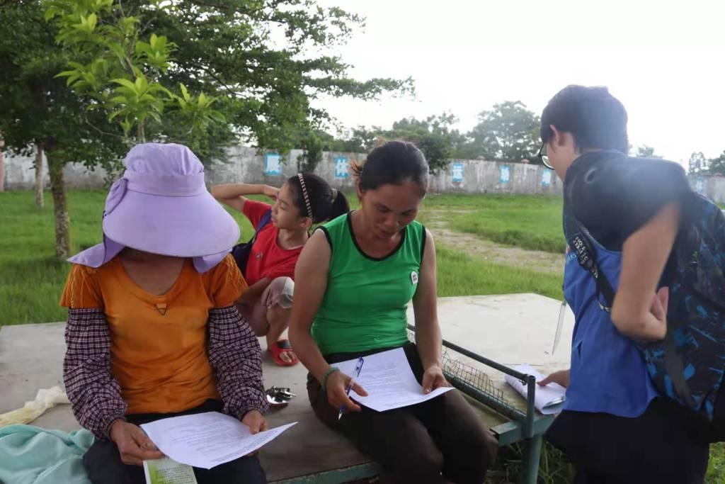 队员向前来接小孩放学的家长介绍义教的活动内容，并请他们填写自闭症情况调查问卷，他们对科普自闭症表达了支持与鼓励。