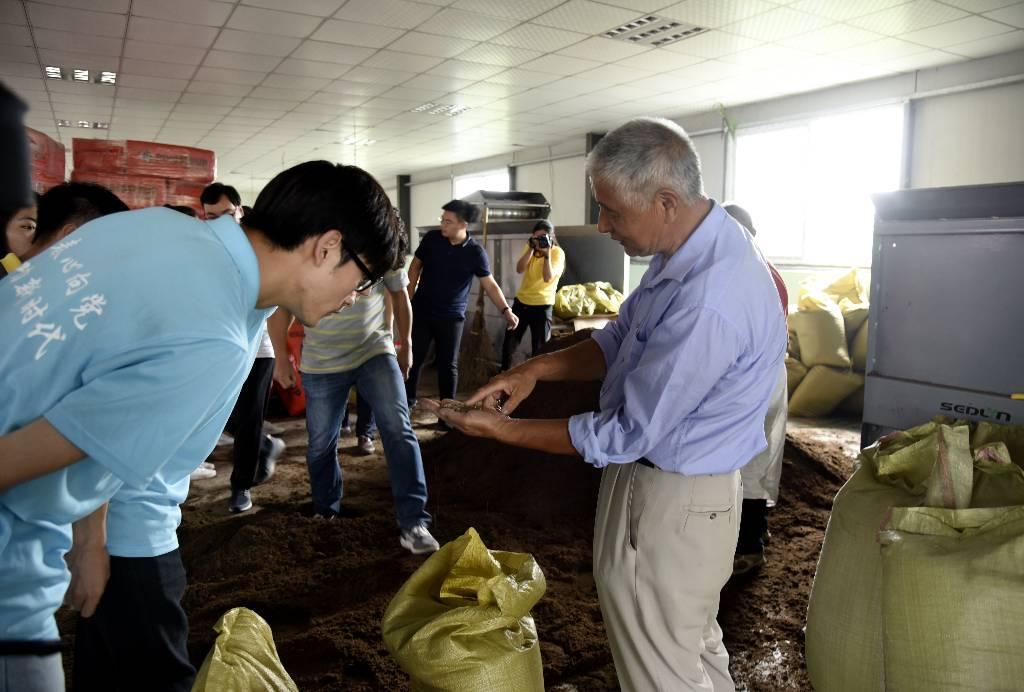 调研团一行参观蔬菜幼苗生产加工现场，技术指导员周师傅将生产材料拿给团队成员观看。